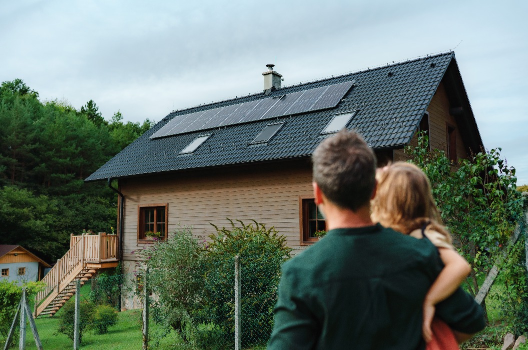 Vater mit Tochter vor Haus mit Photovoltaik
